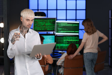 Wall Mural - Male programmer with laptop and cup of coffee in office at night