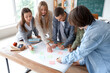 © Pixel-Shot - Group of teenage students performing task at table in classroom