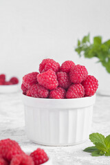 Wall Mural - Bowl with fresh organic raspberry and green mint on a white background. Copy space.