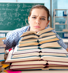 Wall Mural - Female student with many books sitting in the classroom