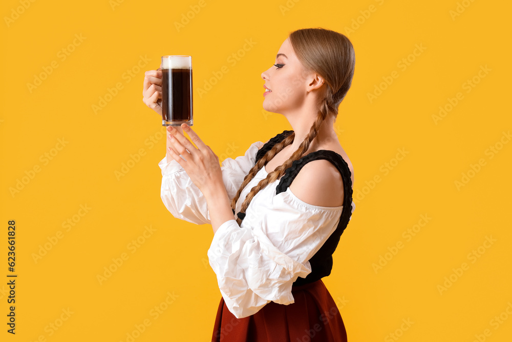 Beautiful Octoberfest waitress with beer on yellow background