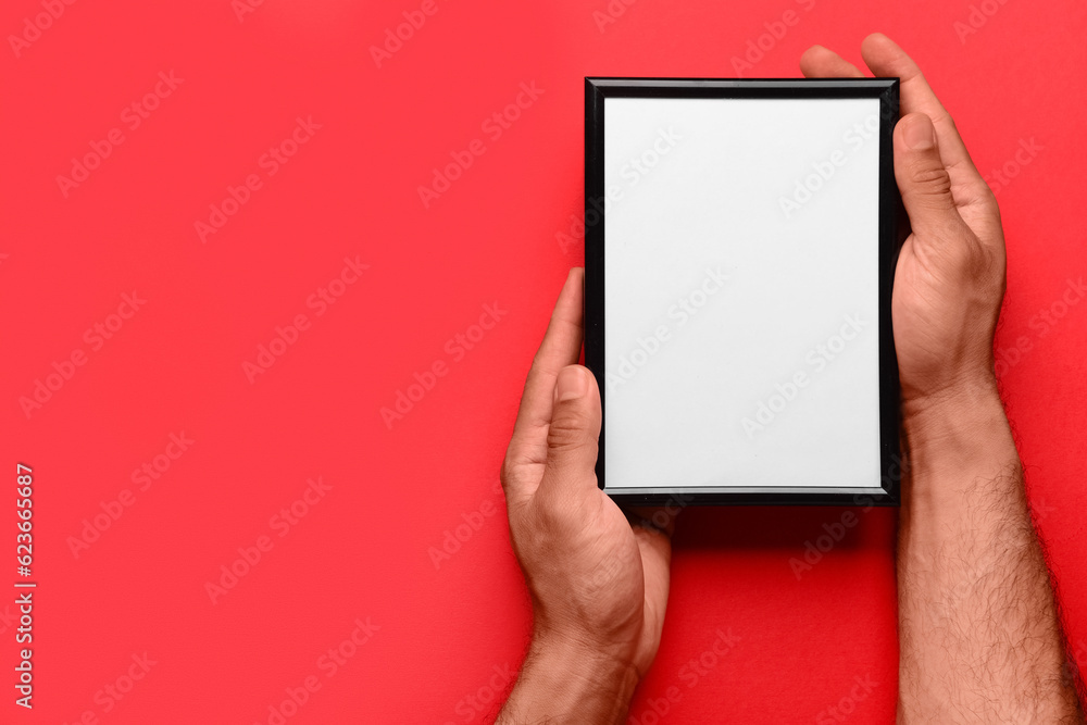 Man holding blank photo frame on red background