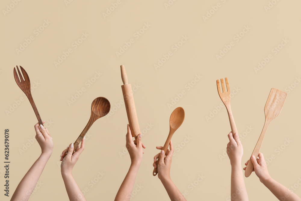 Female hands with wooden baking utensils on beige background