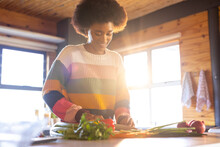 Happy African American Woman Preparing Meal Chopping Vegetables In Sunny Kitchen