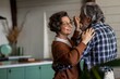 © CinemaF - Happy elderly couple is laughing and dancing in the kitchen on their anniversary day. Old couple have emotional dance while listening good music