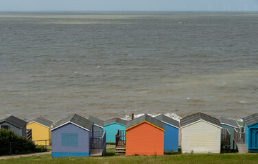 Wall Mural - Colourful holiday wooden beach huts facing the calm ocean.