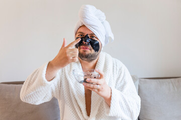 Wall Mural - funny bearded man applying black mask for skin care