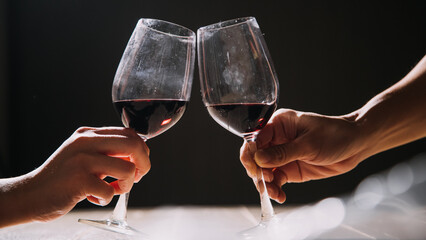 Set of hands holding red wine glass isolated on black background.