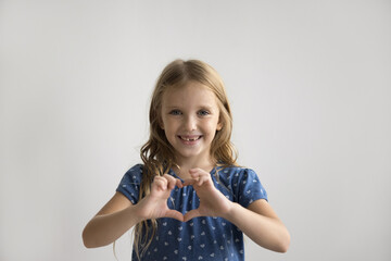 cheerful cute preschool girl joining fingers, making hand heart shape, positive pretty little kid sh