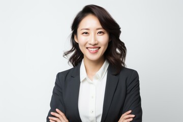 Portrait of a happy young businesswoman standing with arms crossed over white background