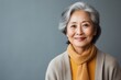 © Anne Schaum - Portrait photography of a satisfied Chinese woman in her 60s wearing a chic cardigan against an abstract background