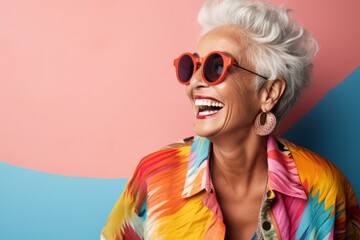 Wall Mural - Portrait of smiling senior woman in sunglasses looking at camera on colorful background