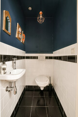 a bathroom with blue walls and white tiles on the wall there is a toilet, sink and mirror in the corner