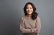 © Robert MEYNER - smiling asian woman in sweater with crossed arms isolated on grey
