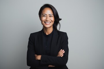 portrait of smiling asian businesswoman with crossed arms isolated on grey