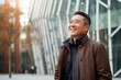 © Robert MEYNER - Portrait of happy asian man in urban background. Cheerful middle-aged man smiling and looking at camera.