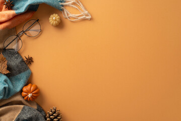 Wall Mural - Above view of a warm and cozy autumn ambiance at home. Glasses, patchy scarf, pumpkin candles, maple foliage and aromatic chinese anise create a perfect brown backdrop for text or advert placement