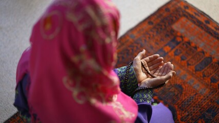 Wall Mural - Closeup of a muslim woman hands while praying with prayer beads on prayer rug.