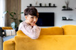 © leszekglasner - Smiling woman on yellow sofa in modern living room looking at camera