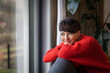 © leszekglasner - Smiling woman sitting on couch and looking through window