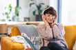 © leszekglasner - Smiling woman listening music on wireless headphones on sofa at home