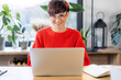 © leszekglasner - Smiling short haired woman with glasses at home office looking at camera