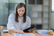© Tj - Sharing good business news. Attractive young businesswoman talking on the mobile phone and smiling while sitting at her working place in office and Checking document.