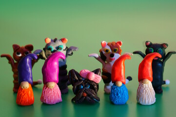 Wall Mural - Figurines of colorful dwarfs, seals and dogs made of plasticine. Green background.