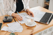 Close-up Hands Of Unrecognizable Woman Work At Home In The Kitchen With Financial Papers, Counting On A Calculator, Paying Bills, Planning A Budget To Find A Way To Save Money. Independent Accounting