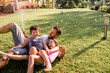 © Geber86 - Single father playing with his two kids in the backyard with a water hose