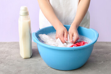 Canvas Print - Woman washing laundry in plastic basin on grey grunge table