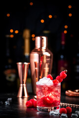 Rosso berry crush alcoholic cocktail drink with red vermouth, raspberries, currants and ice, dark bar counter background, copy space