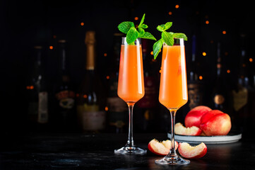 Peach Bellini alcoholic cocktail drink with prosecco, cava, or sparkling wine with peach puree, syrup and ice, dark bar counter background, copy space