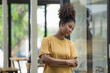 © Songsak C - Young pretty African American standing and arms crossed near a window.