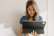 © Sevendeman - Serious asian woman working online with tablet on hotel bed in travel trip
