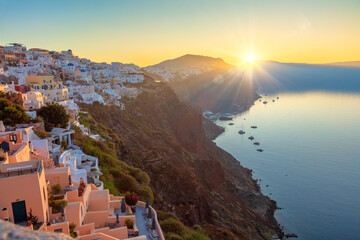 Wall Mural - Santorini, Greece. Sunrise on the famous island of Santorini, view of the city of Oia. The sun rises and illuminates the traditional Greek architecture of Santorini.