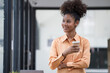© Songsak C - A happy young African American female holding a cup with a hot drink and looking away.