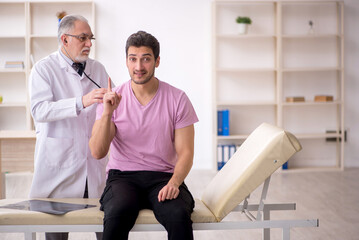 Wall Mural - Young male patient visiting old male doctor