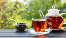 Black Tea In Glass Cup And Teapot On Summer Outdoor Background. Copy Space.