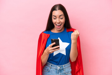 Wall Mural - Super Hero Caucasian woman isolated on pink background surprised and sending a message