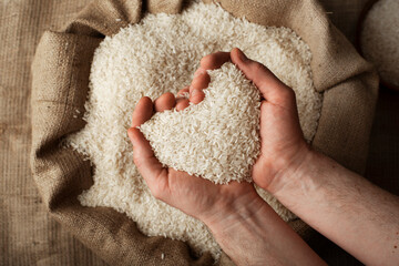 Wall Mural - Human hands in shape of heart holding handful of rice over burlap sack