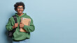 © WHstudio Leushin N - Education concept. Studio photo of young delighted smiling Hindu male student with books and notebooks at hand standing on left isolated on blue background with blank space for your advertisement