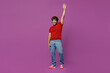 Full body young excited fun smiling happy Indian man he wear red t-shirt casual clothes headphones listen to music raise up hand isolated on plain purple background studio portrait. Lifestyle concept.
