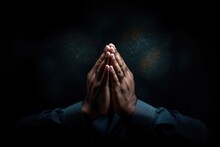 Close Up Of Man Praying With Hands Clasped Together Against Dark Background