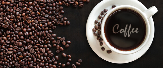 Wall Mural - Coffee Americano. Top view of a cup of coffee on the background of roasted coffee beans. Lettering Coffee in a white cup. Banner