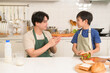 © tonefotografia - Happy Young Asian father and son eating healthy food in kitchen at home