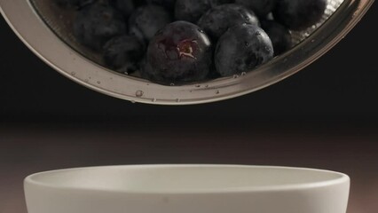 Wall Mural - Slow motion pour washed fresh blueberries from sieve to white bowl