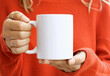 © Gravity Digital - Girl is holding white 11 oz mug in hands with orange sweater. Blank ceramic cup