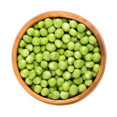 Wall Mural - Fresh green peas, in a wooden bowl. Raw, small spherical seeds of the pod fruit Pisum sativum of greenish and yellowish color, mostly used for soups and as side dish. Isolated, from above, food photo.