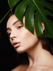 Wall Mural - Beauty Portrait of brunette girl in palm leaves. Beautiful young woman with Make-up